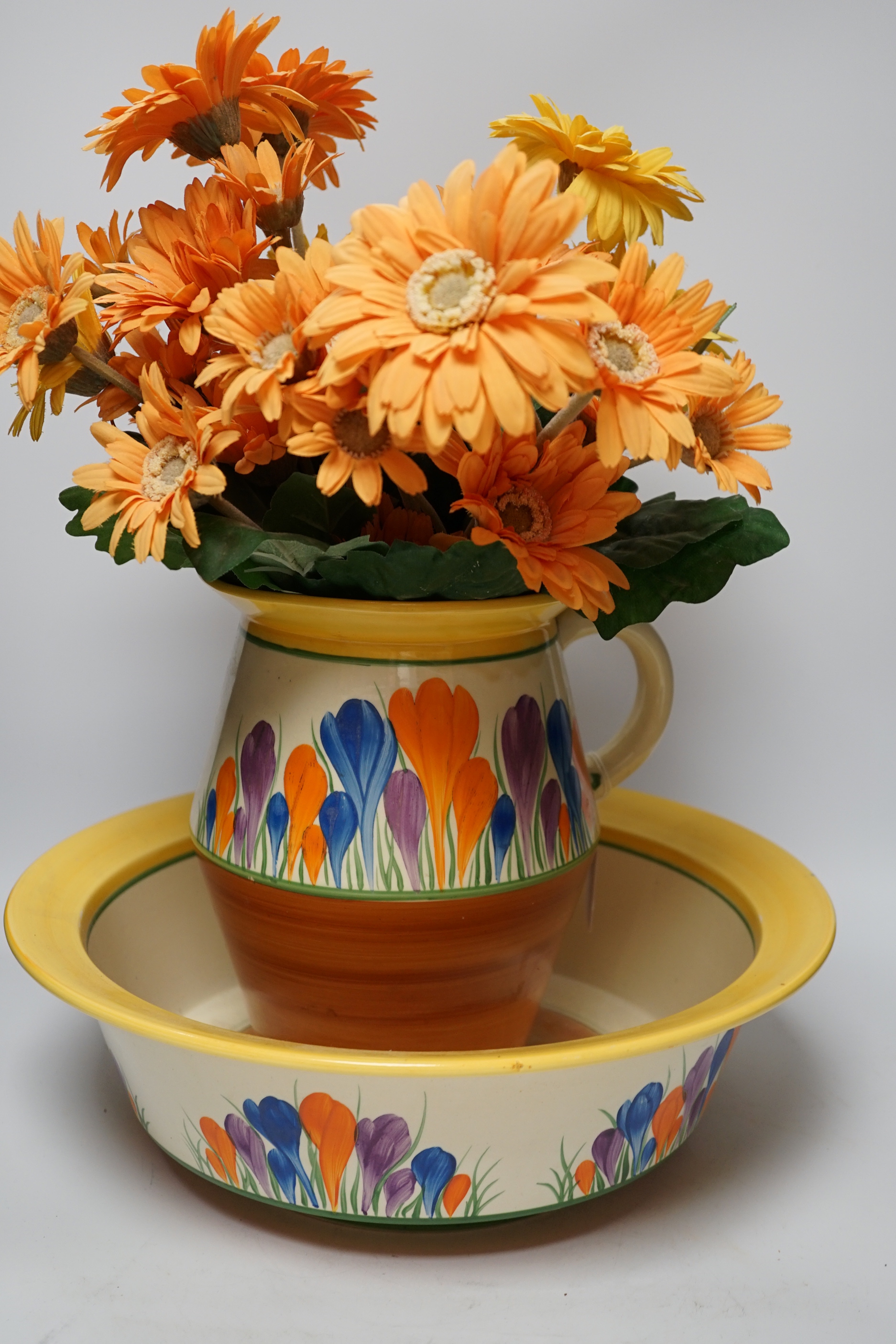 A Clarice Cliff Crocus pattern jug and basin, chamber pot and teapot with cover missing, basin 37cm diameter